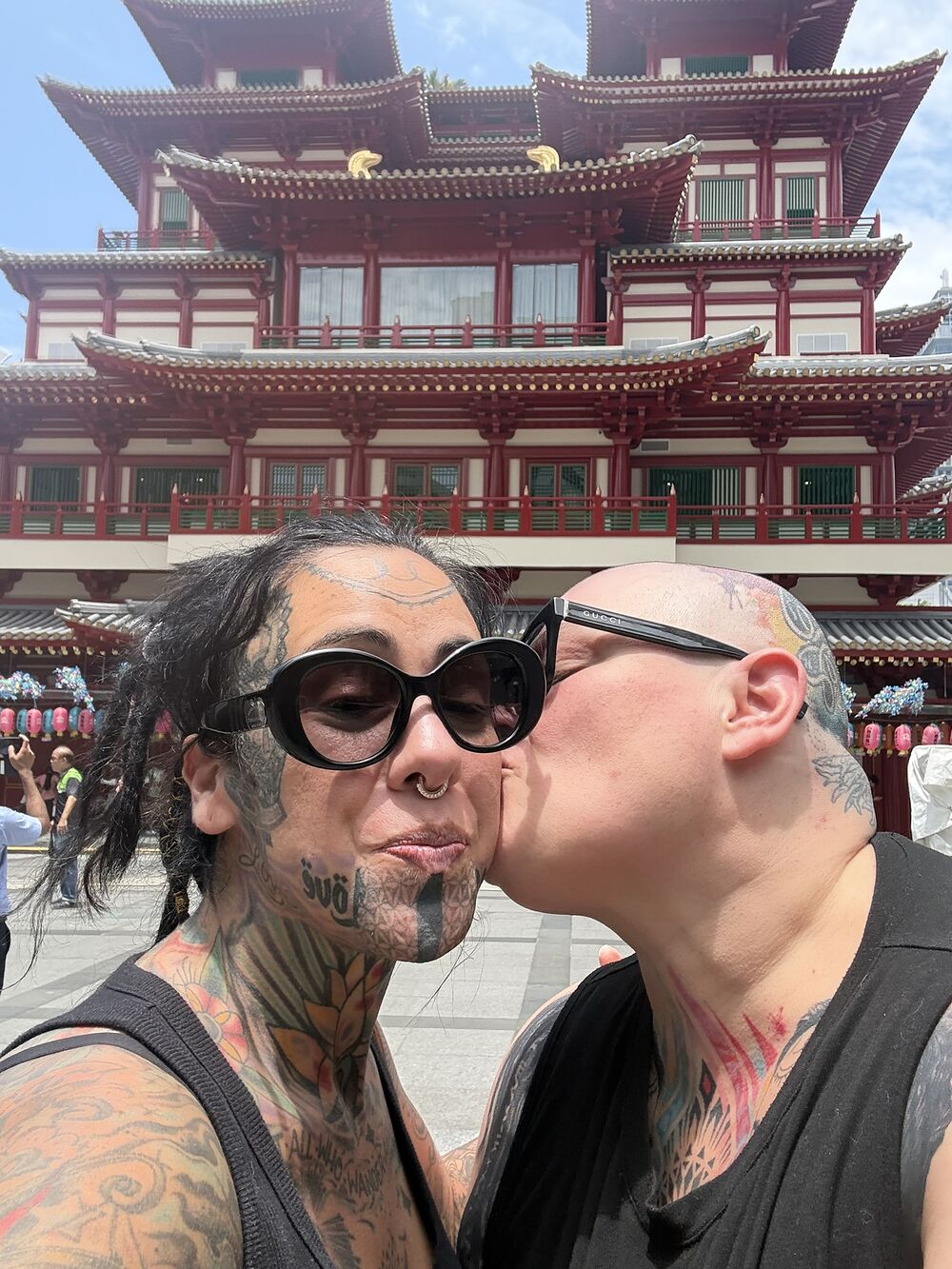Cate and Jenna sharing a kiss in front of a red Chinese temple