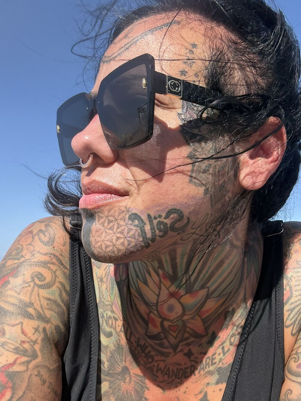 A heavily tattooed face and neck in the sun, the work healed and settled