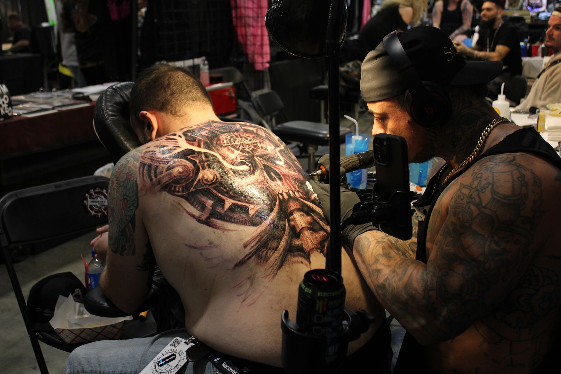 An artist working on a large back piece during a long session